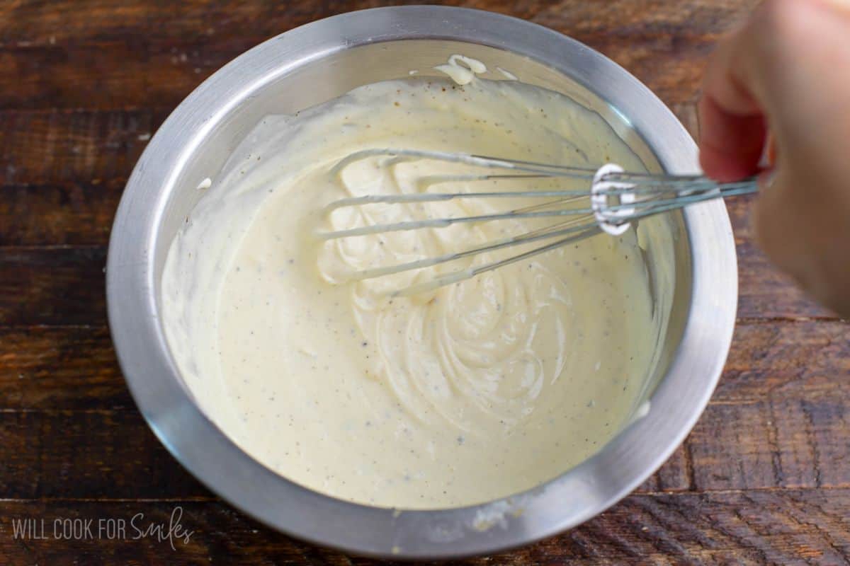 Creamy potato salad dressing whisked together in a mixing bowl until smooth and well combined.