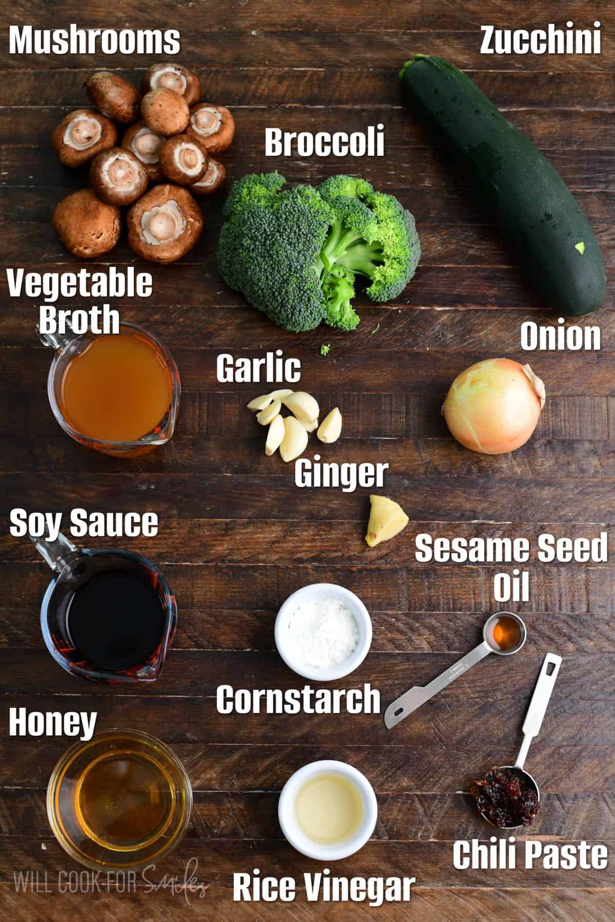Labeled ingredients for zucchini stir fry on a wood surface,