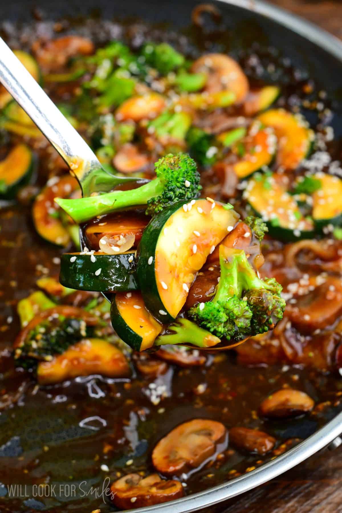 Zucchini stir-fry with broccoli, mushrooms, and onions in savory sauce, topped with sesame and green onion.